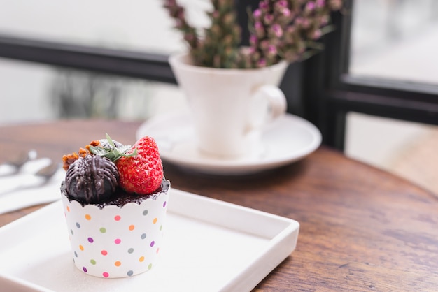 Photo delicious cup cakes with strawberry on table background.