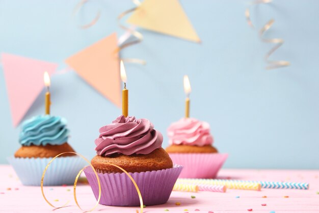 テキストを挿入するスペースのある色付きの背景にキャンドルが付いたおいしいカップケーキ。お祭りの背景、誕生日。高品質の写真