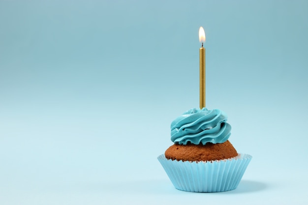 Delicious cupcake with a candle on a colored background with space to insert text