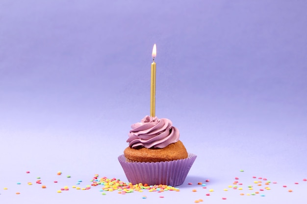 Delicious cupcake with a candle on a colored background with space for text