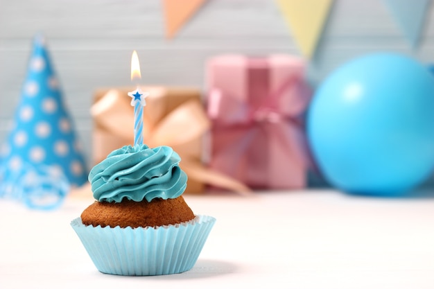 Delicious cupcake with a candle on a colored background