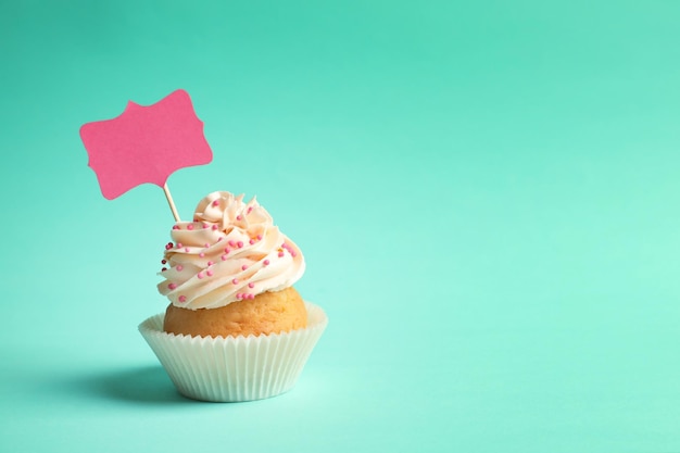 Photo delicious cupcake with greeting card on color background