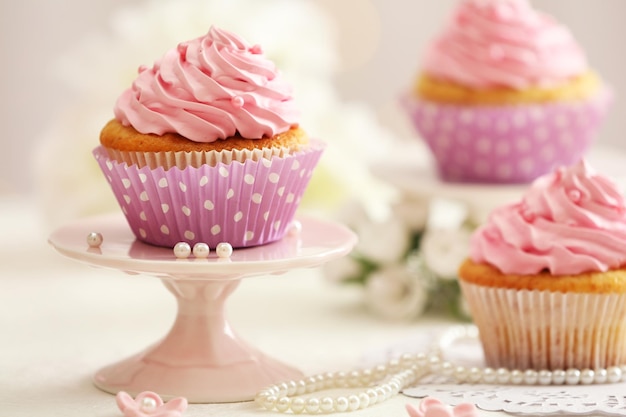 Delicious cupcakes on table on light background