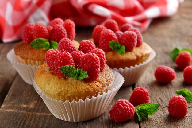 Delicious cupcakes with berries and fresh mint on wooden table close up