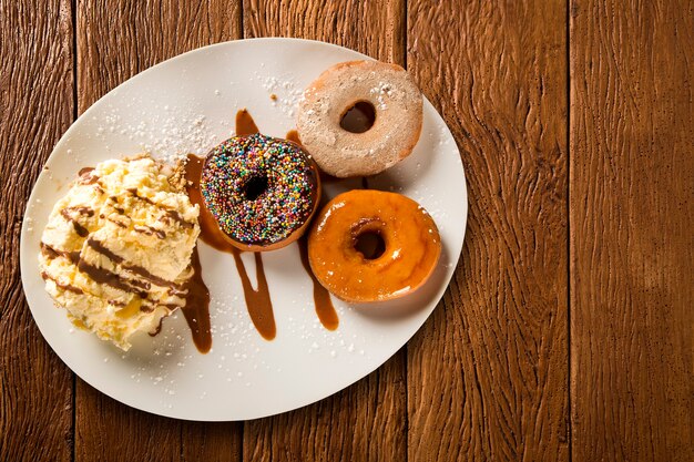 Delicious dessert donuts with ice cream on a white plate with decoration on a wooden table