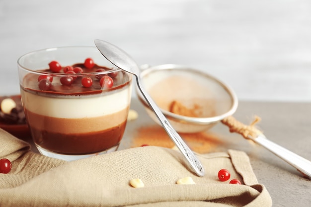 Delicious dessert with rowan in glass on table