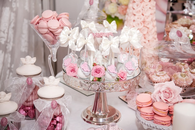 Deliziosi dessert al wedding candy bar nell'area buffet: cake pops decorati con angeli e cammei e freschi boccioli di rosa.