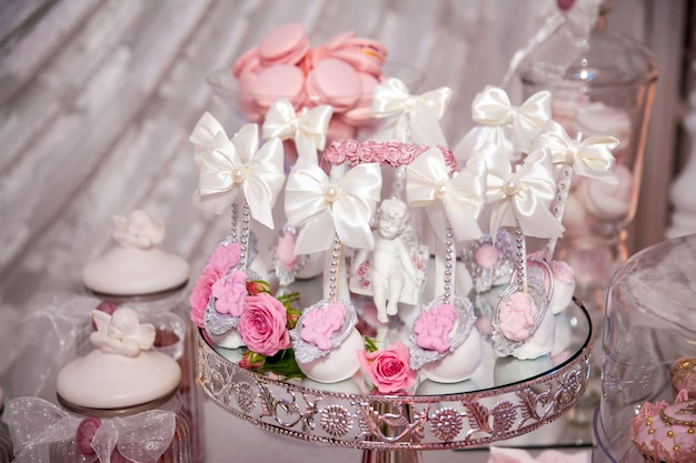 Delicious desserts at the wedding candy bar in the buffet area: cake pops decorated with angels and cameo and fresh rosebuds