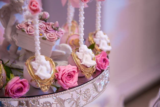 Delicious desserts at the wedding candy bar in the buffet area: cake pops decorated with angels and cameo and fresh rosebuds