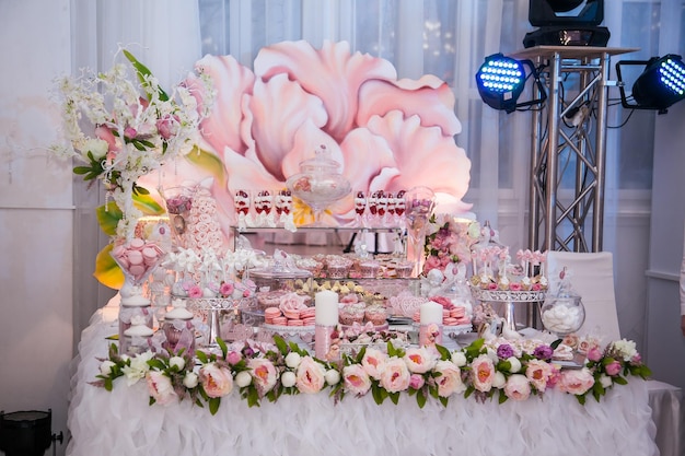 Delicious desserts at the wedding candy bar in the buffet area decorated candles rosebuds ribbons macaroons strawberries in white chocolate