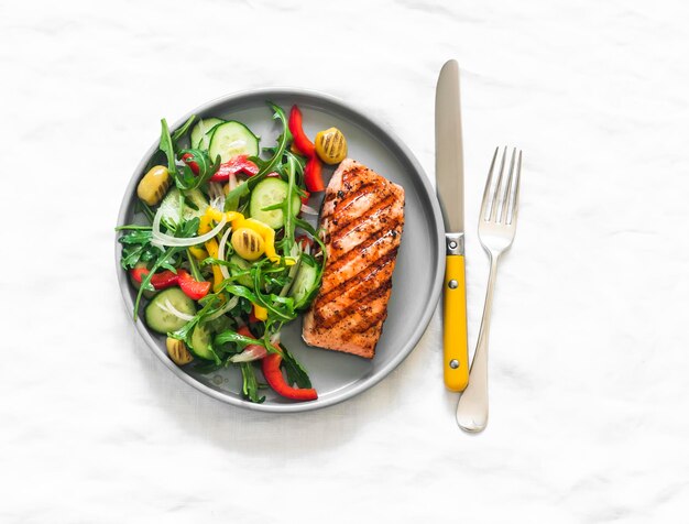 Photo delicious diet lunch dinner grilled salmon and fresh vegetable salad on a light background top view