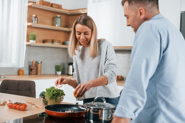 Foto cena deliziosa coppia che prepara il cibo a casa sulla cucina moderna