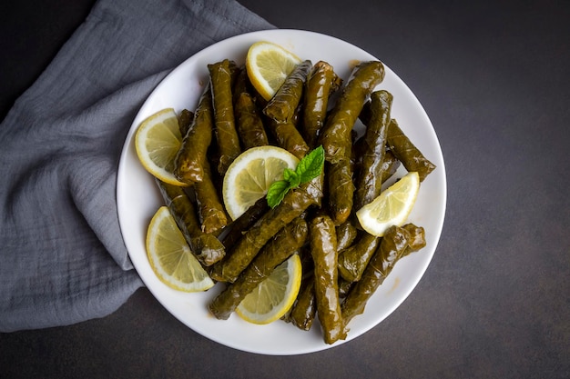 Delicious dolma (sarma) stuffed grape leaves rice, white yogurt sauce. Lebanese dolma sarma on plate. Lebanon turkish greek middle eastern cuisine. (Turkish name; Yaprak sarma)