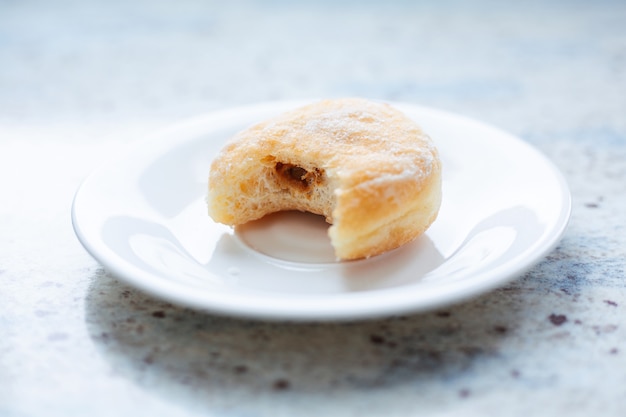 Delicious donut on plate with bitemark