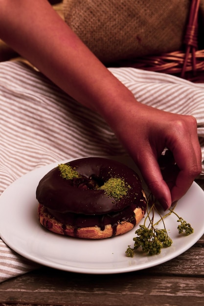 Delicious donut with chocolate sauce and pistachio nut pieces.