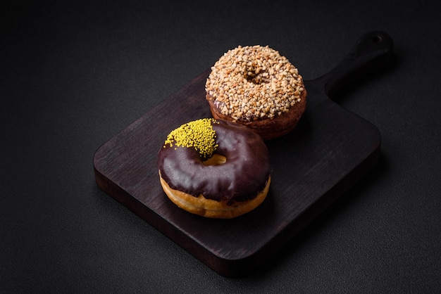 Delicious donut with cream filling and nuts on a dark concrete background