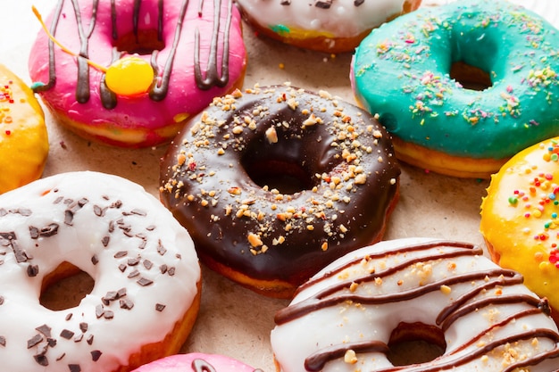 Delicious donuts of different flavors on paper close up