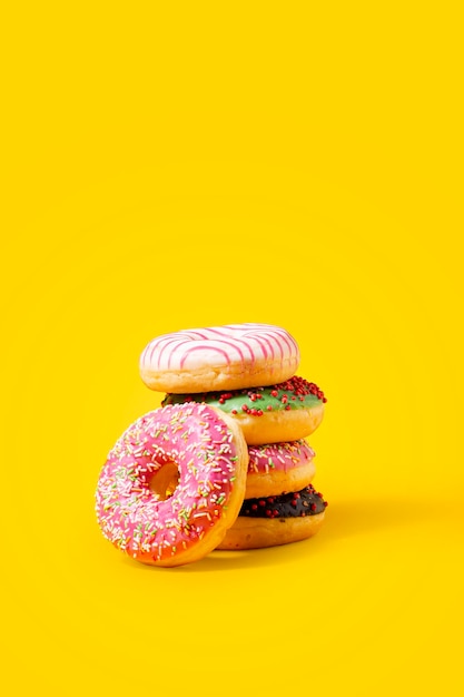 Фото Вкусные пончики, изолированные на желтом фоне