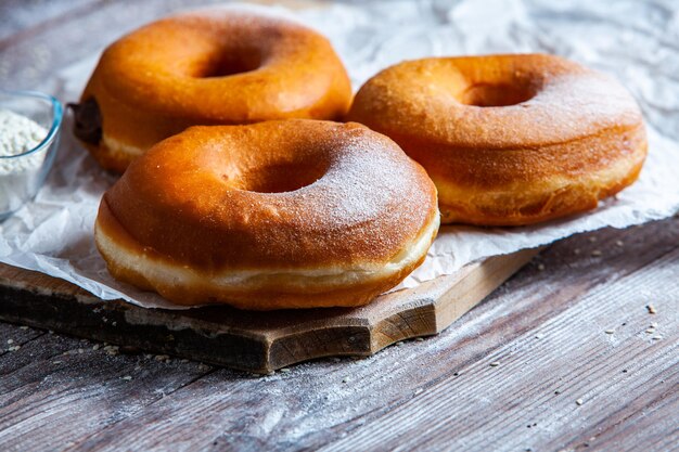 Delicious donuts with powdered sugar on wooden table