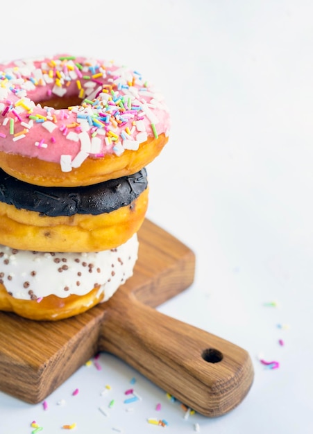 Delicious donuts on wooden board placed on wooden cutting board on white background