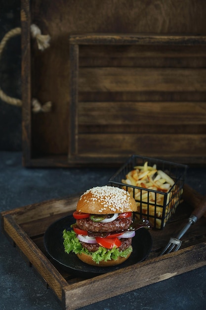 暗い背景にフライドポテトとおいしいダブルバーガー、雰囲気のあるレストラン、食べ物の写真