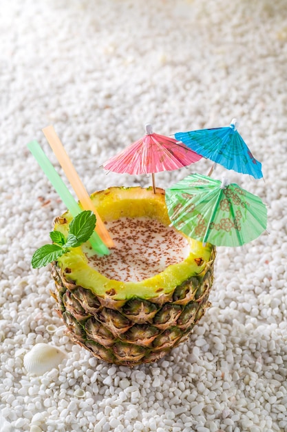 Delicious drink in pineapple with cocktail umbrellas