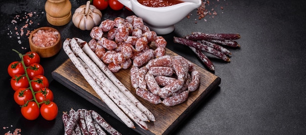 Delicious dry sausage with walnuts on a concrete table Dry cured fuet sausage on a dark background