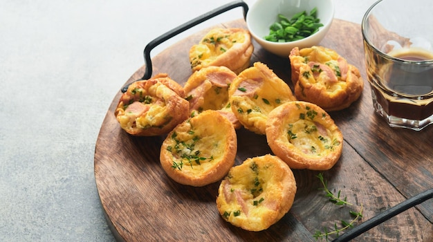 Delicious egg muffins with green onions bacon cheese and tomatoes on wooden board on light background Healthy high protein and low carb breakfast Homemade food