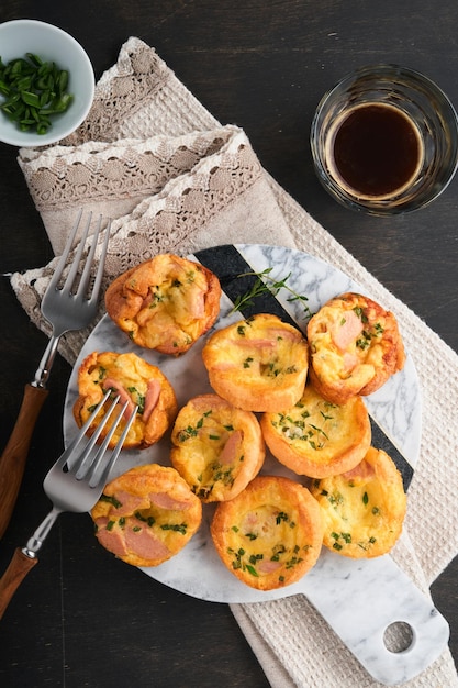 Delicious egg muffins with green onions bacon cheese and tomatoes on wooden board on old wooden rustic background Healthy high protein and low carb breakfast Homemade food