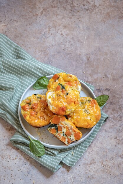 Foto deliziosi muffin all'uovo con patate dolci, spinaci e cipolla