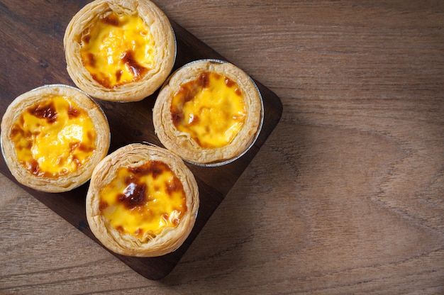 Delicious Egg tart, Portuguese dessert, on wooden plate for coffee break 