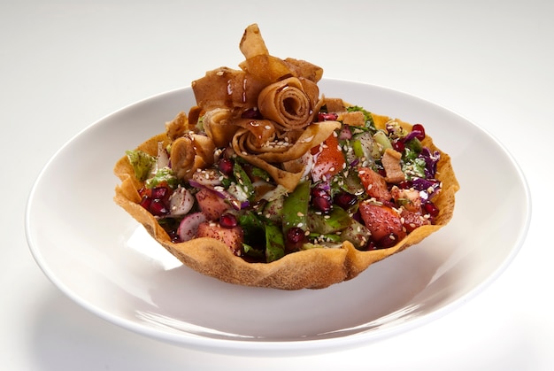 Delicious Fattoush or Arab salad with pita croutons, fresh vegetables and herbs, on white plate. Middle Eastern bread salad. Easy and healthy authentic recipe.