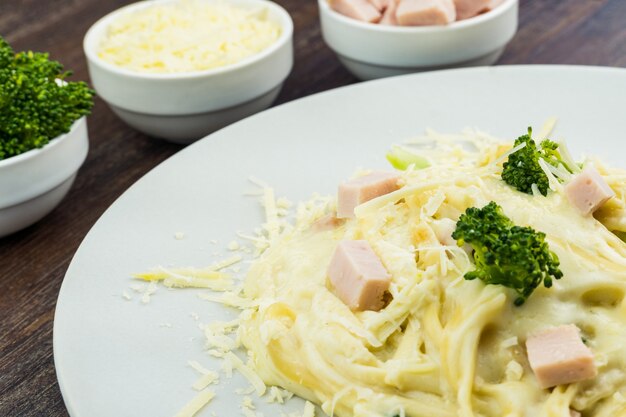 Delicious Fettuccine with white sauce, broccoli, turkey breast cubes and grated cheese. Selective focus.