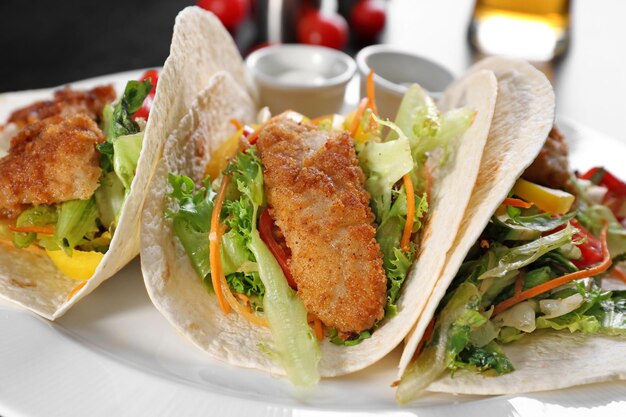 Delicious fish tacos on white plate close up