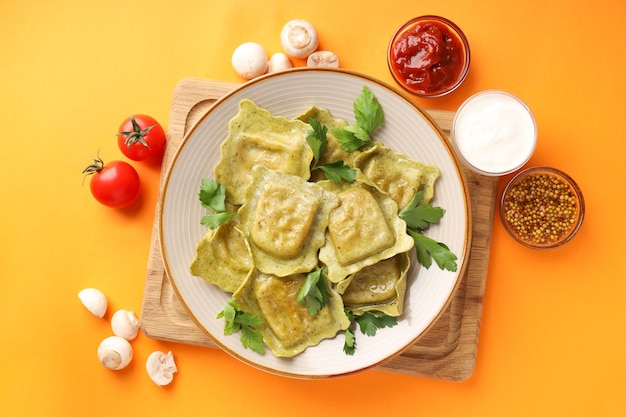 Delicious food concept with ravioli on orange background