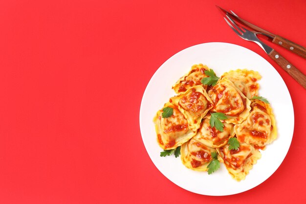 Delicious food concept with ravioli on red background