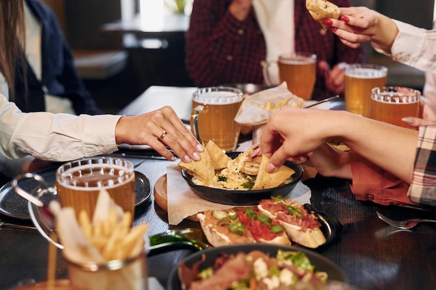 おいしい食べ物 ビールを飲みながらバーに一緒に座っている若い友人のグループ