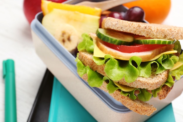 Delicious food in lunch box and stationery on light background