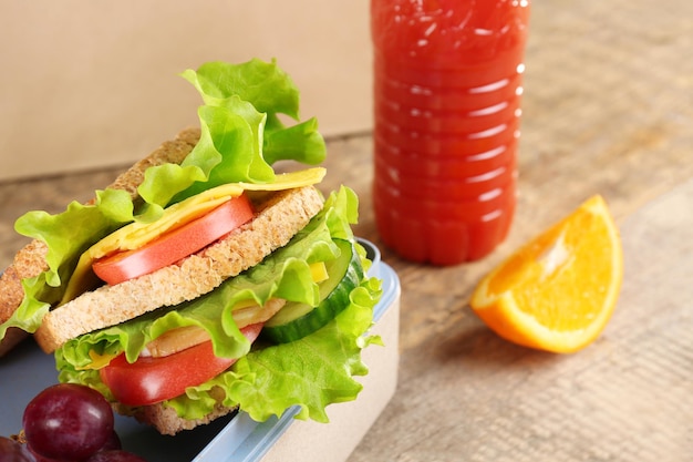 Delicious food in lunch box on wooden background