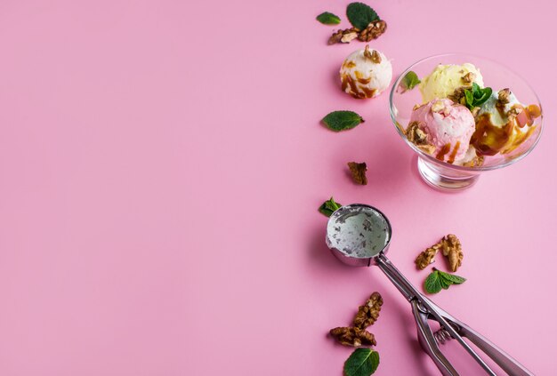 Delicious fragrant ice cream with nuts and mint on a pink surface
