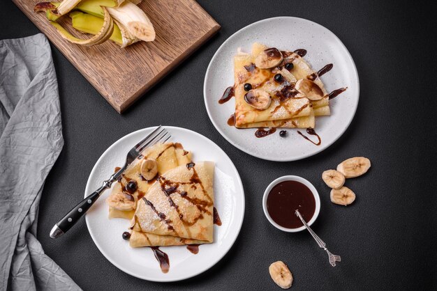 Delicious fresh baked pancakes with honey and fruits on a concrete background