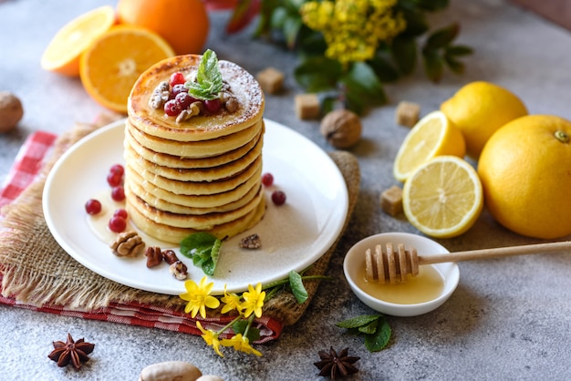 Delicious fresh beautiful pancakes with citrus honey and jam. Delicious hot breakfast with pancakes with fruit and berries