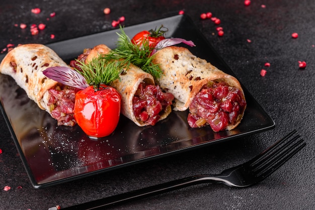 Delicious fresh beef tartar with toasts on a black square plate against a dark surface