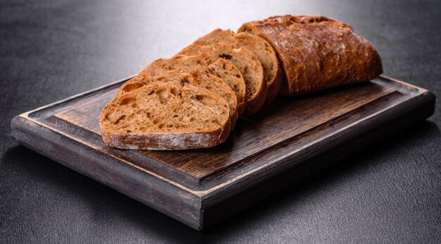 Delicious fresh black bread sliced with slices on a dark concrete background. Preparation of sandwiches