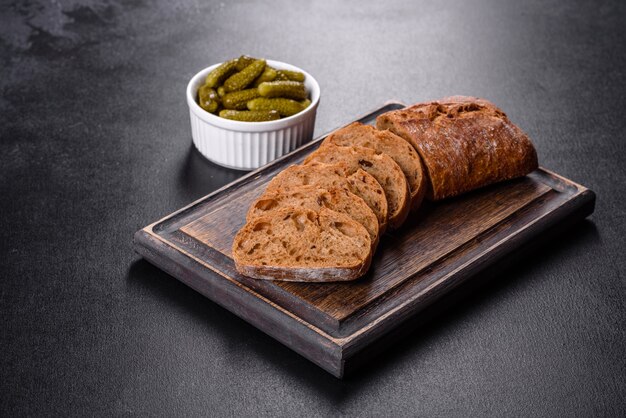 Delicious fresh black bread sliced with slices on a dark concrete background. Preparation of sandwiches