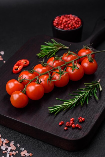 Delicious fresh cherry tomatoes on a twig on a dark concrete background