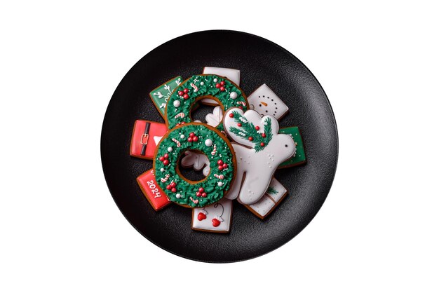 Delicious fresh colorful Christmas or New Year gingerbread cookies on a ceramic plate on a dark concrete background