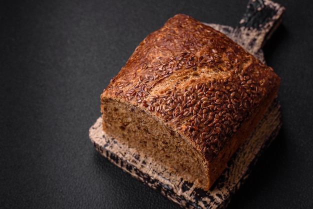 Delicious fresh crispy brown bread with grains and seeds on a dark concrete background