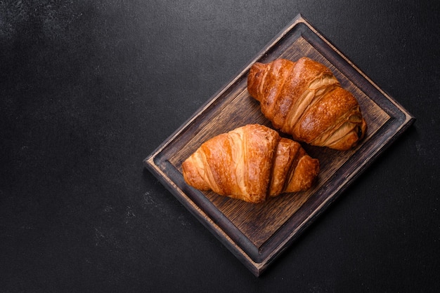 Delicious fresh crispy croissants on a dark concrete background. Tasty breakfast