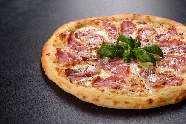 Delicious fresh crispy pizza from the oven with ham, cheese and basil. Italian cuisine